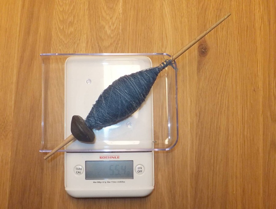 The yarn cop has grown so much that it now touches the whorl. Empty weight of the spindle was 35.4 g, so there's about 20 g very finely spun yarn on this spindle. 